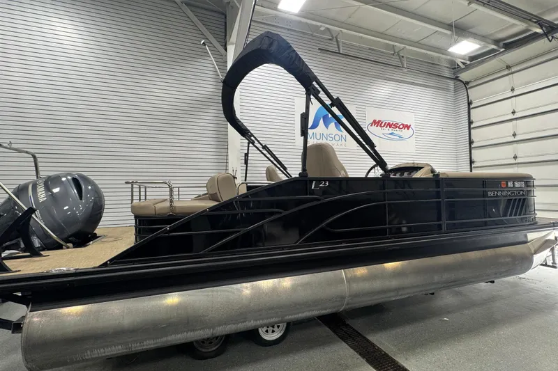Slide: The Image of 2024 Bennington 24 L Swingback pontoon boat in showroom, featuring sleek black design. - 4