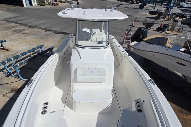 Slide: The Image of 2018 Edgewater 280CC boat on dry dock, showcasing spacious deck and helm station. - 10