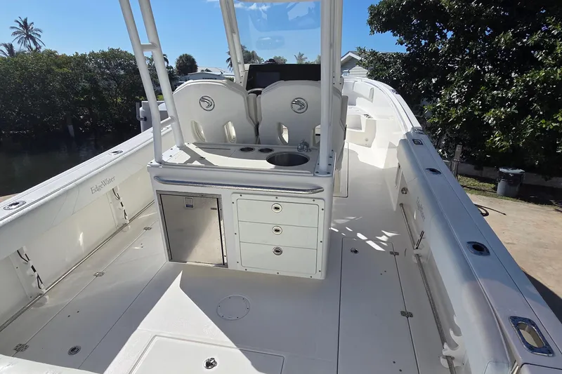 Slide: The Image of 2018 Edgewater 280CC boat interior with seating, storage, and sink under clear blue sky. - 5