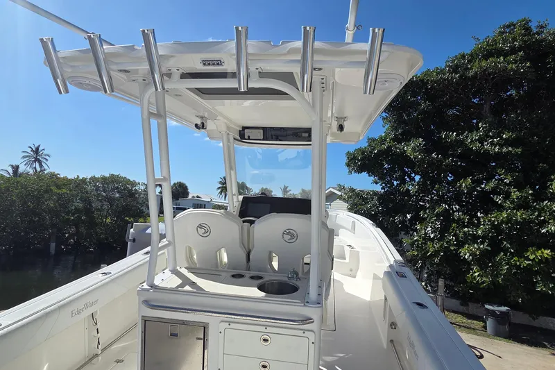 Slide: The Image of 2018 Edgewater 280CC boat with T-top, docked near lush greenery. - 6