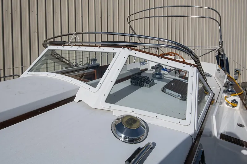 Slide: The Image of 1999 Gozzard 37A sailboat deck with winches and steering wheel, docked near a beige wall. - 11