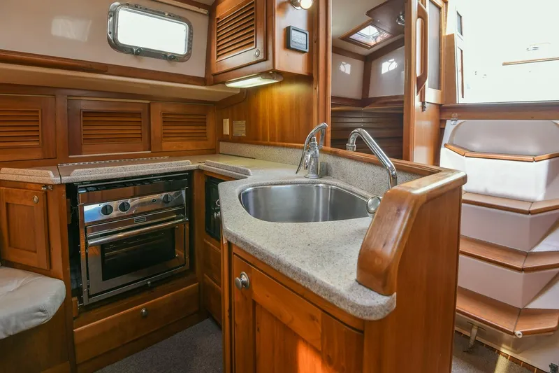 Slide: The Image of Interior of 1999 Gozzard 37A yacht featuring a compact wooden kitchen with sink and stove. - 26
