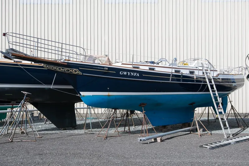 Slide: The Image of 1999 Gozzard 37A sailboat on stands, blue hull, ladder beside it. - 3