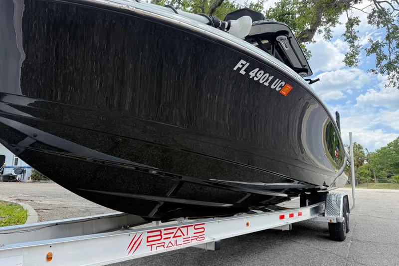 Slide: The Image of 2025 Caymas 281 HB boat on trailer, sleek black hull, parked outdoors. - 14