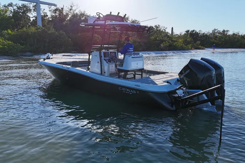 Slide: The Image of 2025 Caymas 281 HB boat on calm water near a lush shoreline. - 2