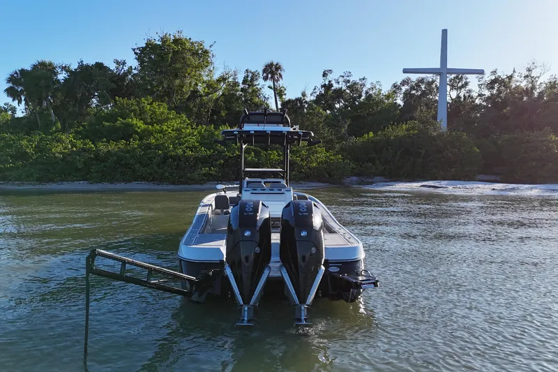 Slide: The Image of 2025 Caymas 281 HB boat docked near a lush shoreline with a large cross. - 3