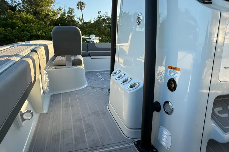 Slide: The Image of 2025 Caymas 281 HB boat interior with seating and rod holders, surrounded by lush greenery. - 47