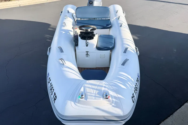 Slide: The Image of 2018 Brig Falcon 360 inflatable boat with seating and steering console, parked on pavement. - 11