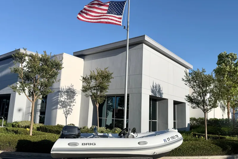 Slide: The Image of 2018 Brig Falcon 360 inflatable boat displayed outside modern building with American flag. - 20