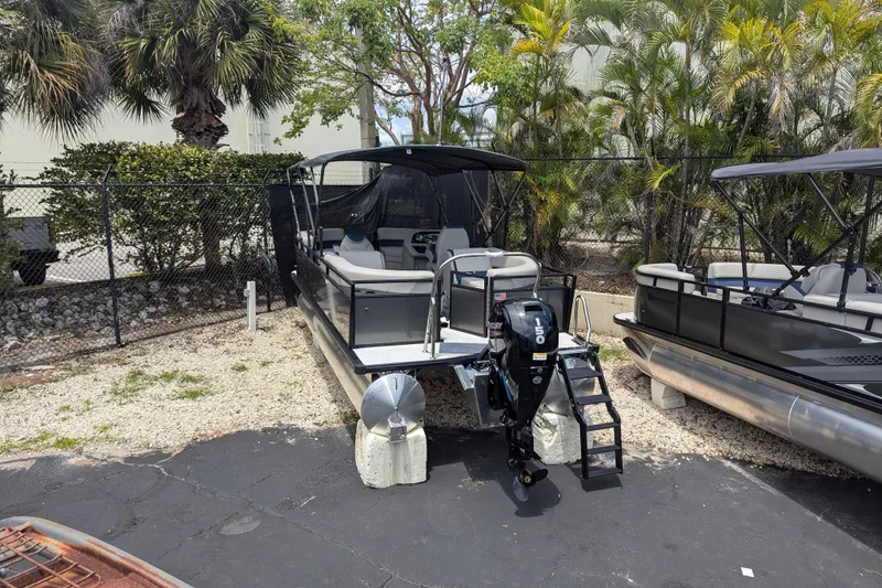 Slide: The Image of 2026 Dockside 22DQ2.75 pontoon boat with outboard motor, parked outdoors. - 2