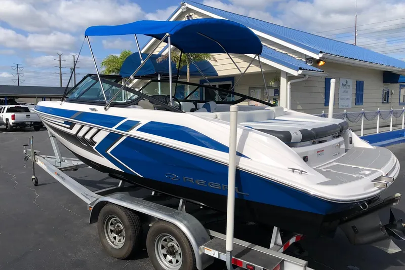 Slide: The Image of 2015 Regal 2000 ESX Bowrider with blue accents on a trailer, parked outdoors. - 10