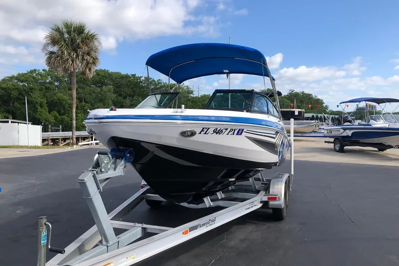 Slide: The Image of 2015 Regal 2000 ESX Bowrider on trailer, blue canopy, parked outdoors. - 2