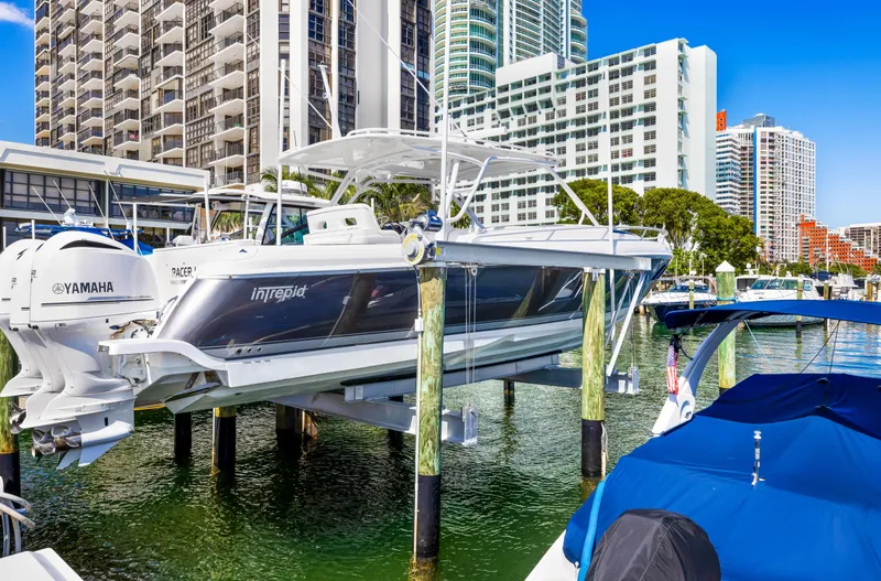 The Image of 2016 Intrepid 400 Cuddy boat docked in a marina with cityscape background. - 0