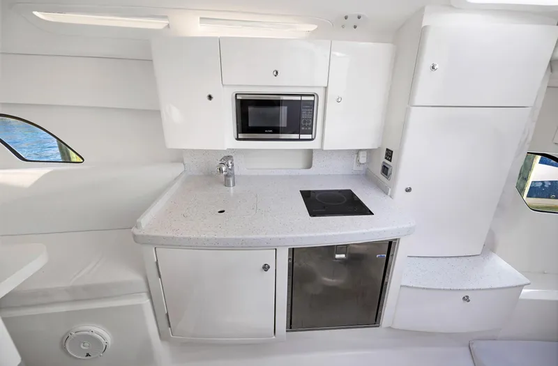 Slide: The Image of 2016 Intrepid 400 Cuddy kitchen area with microwave, stove, and refrigerator. - 27