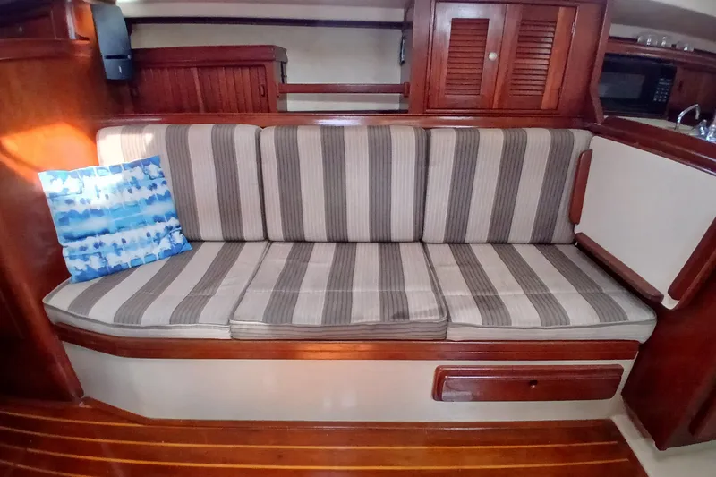 Slide: The Image of Interior of 1995 Island Packet 37 sailboat with striped cushions and wooden cabinetry. - 13