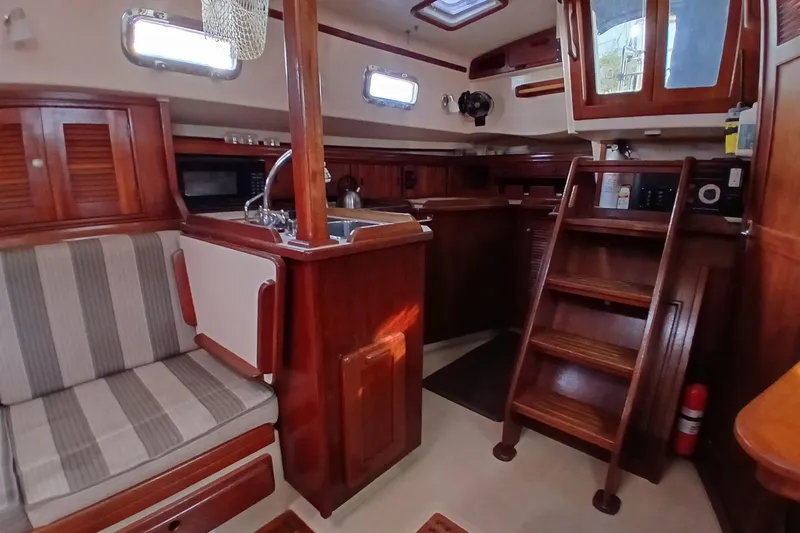 Slide: The Image of Interior of a 1995 Island Packet 37 sailboat with wooden finishes and compact kitchen. - 14