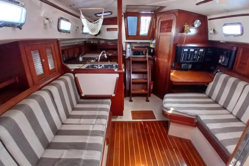 Slide: The Image of Interior of a 1995 Island Packet 37 sailboat with striped seating and wooden finishes. - 17