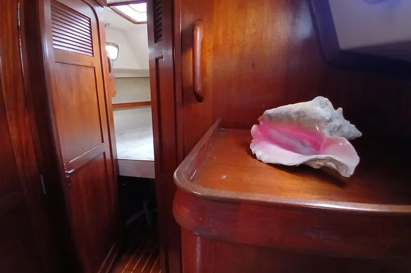 Slide: The Image of Interior of 1995 Island Packet 37 sailboat with wooden cabinetry and conch shell decor. - 19