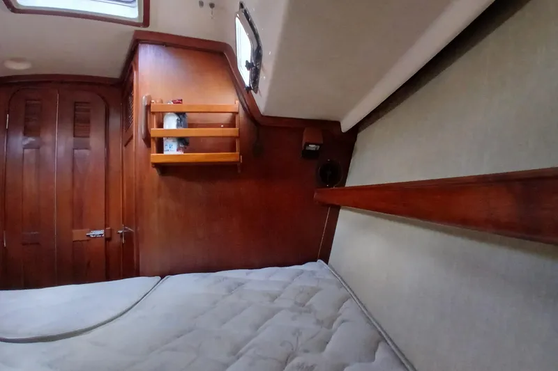 Slide: The Image of Interior cabin of a 1995 Island Packet 37 sailboat with wooden shelves and cozy bedding. - 22