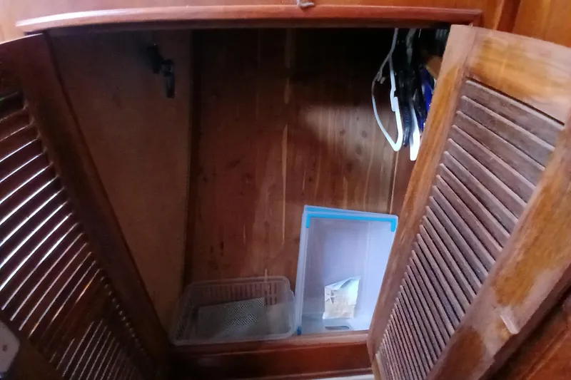 Slide: The Image of Wooden cabinet interior on a 1995 Island Packet 37 sailboat, featuring storage items. - 25
