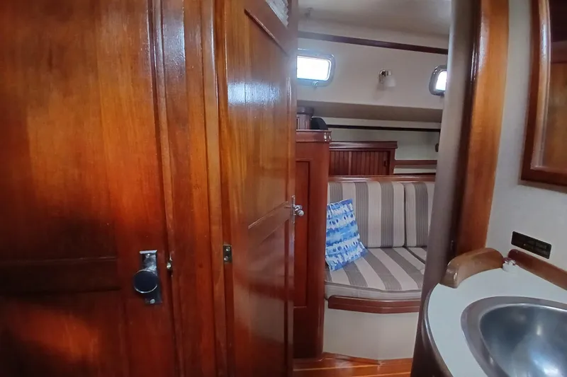 Slide: The Image of Interior of 1995 Island Packet 37 sailboat with wooden cabinetry and striped seating. - 27