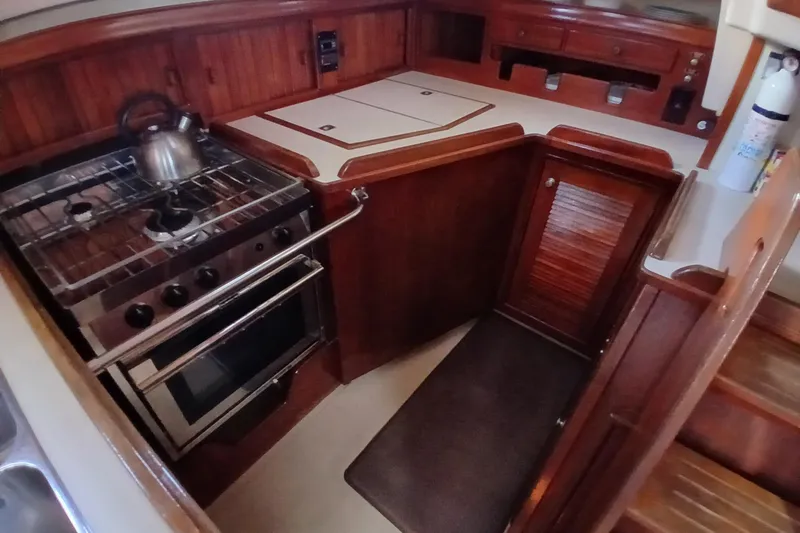Slide: The Image of 1995 Island Packet 37 yacht galley with stove, oven, and wooden cabinetry. - 32
