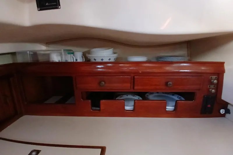 Slide: The Image of Interior of 1995 Island Packet 37 sailboat galley with wooden cabinetry and dish storage. - 34