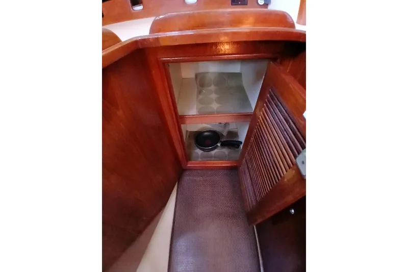 Slide: The Image of Interior storage cabinet on a 1995 Island Packet 37 sailboat, featuring wooden finish and shelves. - 36