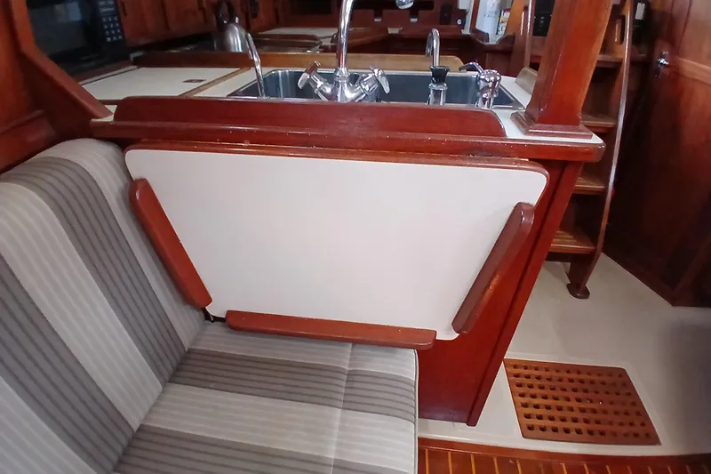 Slide: The Image of Interior of 1995 Island Packet 37 sailboat with wooden cabinetry and striped seating. - 37
