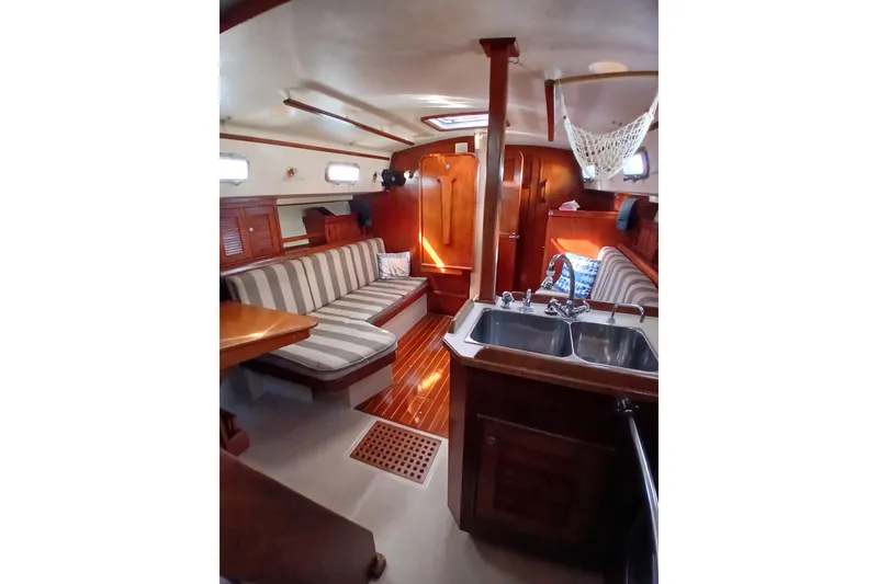 Slide: The Image of Interior of a 1995 Island Packet 37 sailboat with striped seating and wooden finishes. - 39