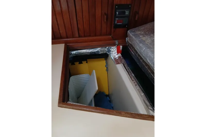 Slide: The Image of Storage compartment in 1995 Island Packet 37 sailboat with wooden paneling and various items. - 40