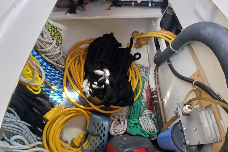 Slide: The Image of Storage compartment of a 1995 Island Packet 37 sailboat with ropes and hoses. - 57