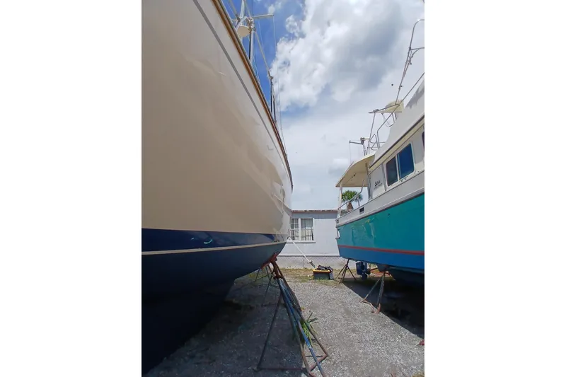 Slide: The Image of Two boats on stands, including a 1995 Island Packet 37, under a cloudy sky. - 65