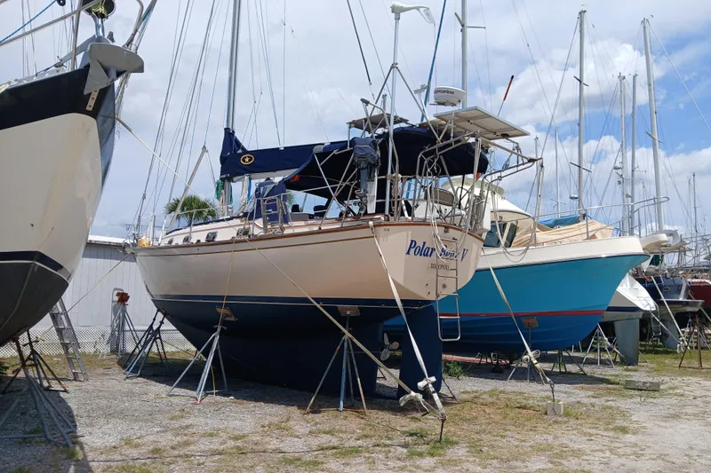 Slide: The Image of 1995 Island Packet 37 sailboat on stands in a boatyard, surrounded by other vessels. - 68