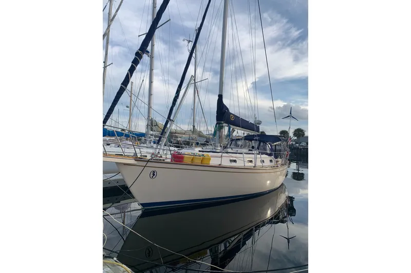 Slide: The Image of 1995 Island Packet 37 sailboat docked in a marina, reflecting on calm water. - 77