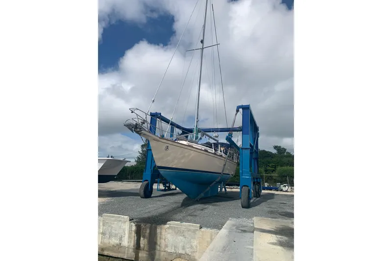 Slide: The Image of 1995 Island Packet 37 sailboat on a lift, under a cloudy sky. - 80