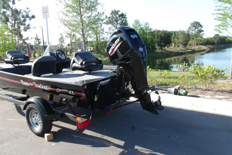 Slide: The Image of 2026 Tracker Bass Tracker Classic XL boat with Mercury engine by a scenic lake. - 8
