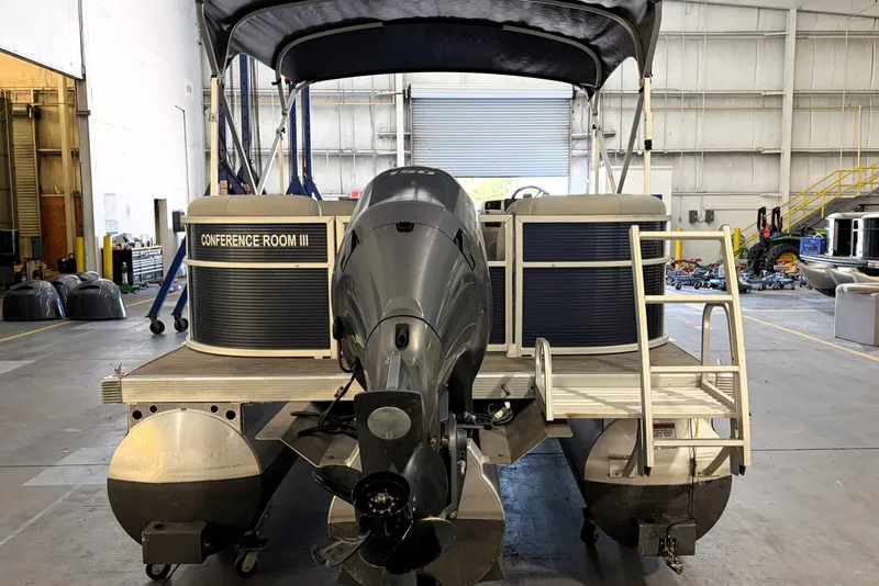 Slide: The Image of 2023 Bennington S22 pontoon boat in a warehouse, rear view with motor and canopy. - 12