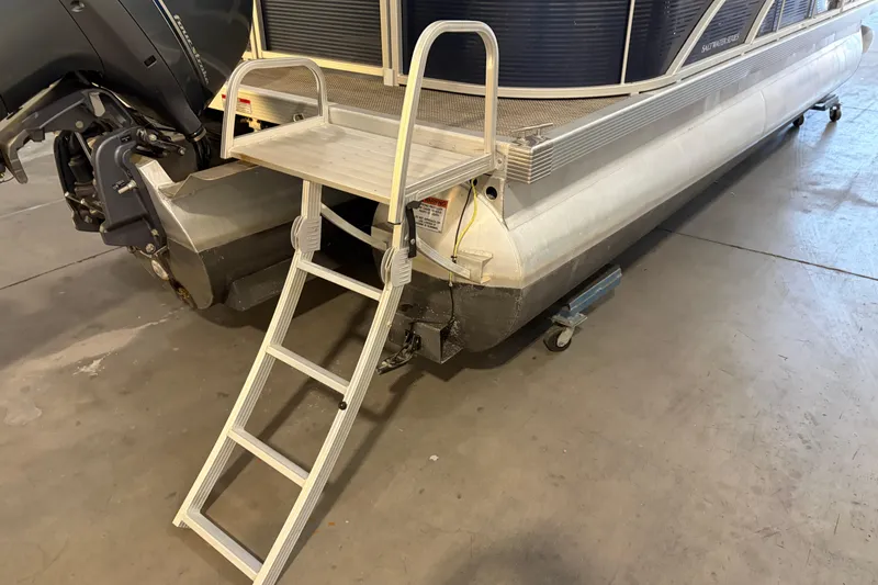 Slide: The Image of 2023 Bennington S22 pontoon boat with ladder and motor in a garage setting. - 13