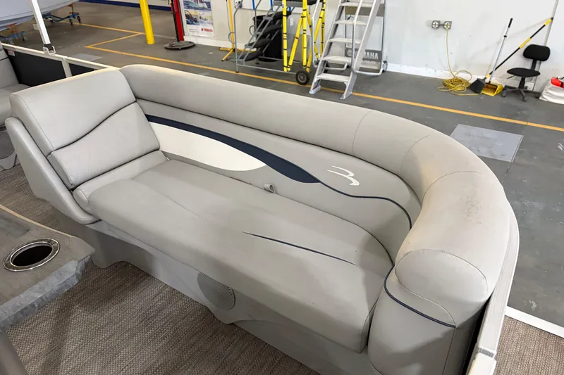 Slide: The Image of 2023 Bennington S22 boat interior with gray cushioned seating in a workshop setting. - 19