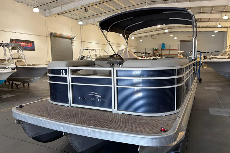 Slide: The Image of 2023 Bennington S22 pontoon boat in a showroom, featuring sleek design and spacious seating. - 7