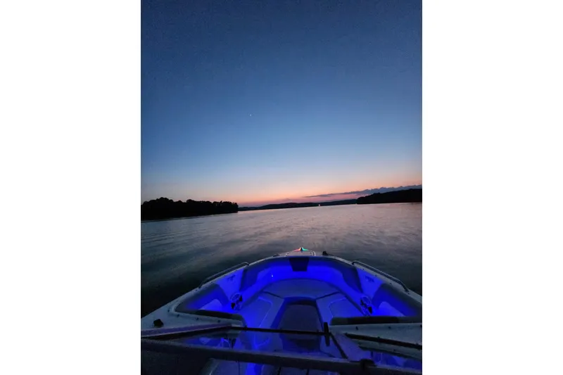 Slide: The Image of 2019 Chaparral 23 H2O Sport boat at sunset with blue interior lights on a calm lake. - 16