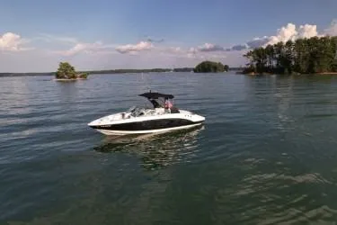 Slide: The Image of 2019 Chaparral 23 H2O Sport boat cruising on a serene lake under a clear sky. - 18