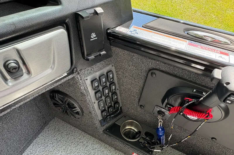 Slide: The Image of Interior controls of 2026 Lund 2075 Pro-V Sport boat, featuring switches and cup holder. - 24