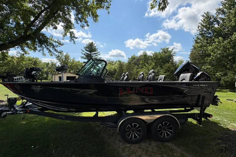 Slide: The Image of 2026 Lund 2075 Pro-V Sport boat on trailer, parked on grassy area under trees. - 4