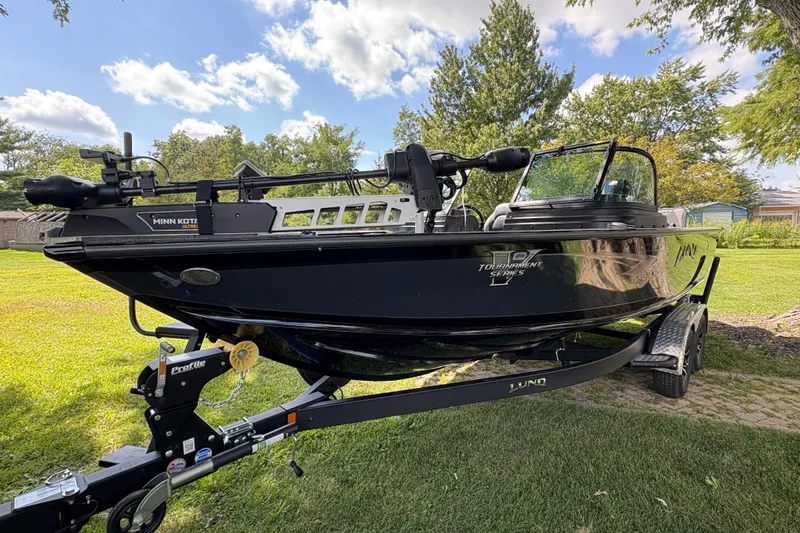Slide: The Image of 2026 Lund 2075 Pro-V Sport boat on trailer, parked on grass under a clear sky. - 5