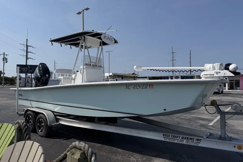 The Image of 2021 Intruder 23 boat on trailer in parking lot, featuring a T-top and outboard motor. - 1
