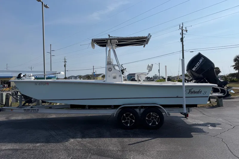 Slide: The Image of 2021 Intruder 23 boat on trailer with Suzuki outboard motor, parked outdoors. - 3