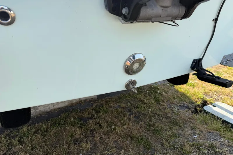 Slide: The Image of Close-up of a 2021 Intruder 23 boat's exterior details, showing metal fittings and grassy ground. - 33