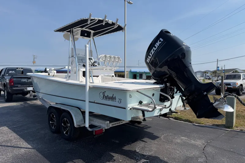 Slide: The Image of 2021 Intruder 23 boat on trailer with Suzuki outboard motor in parking lot. - 4